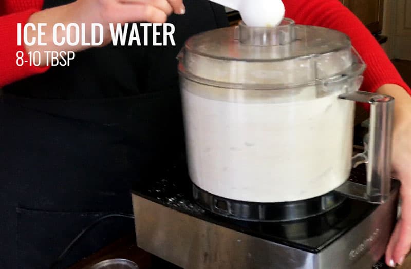 Adding tablespoon by tablespoon of ice cold water to the flour mixture