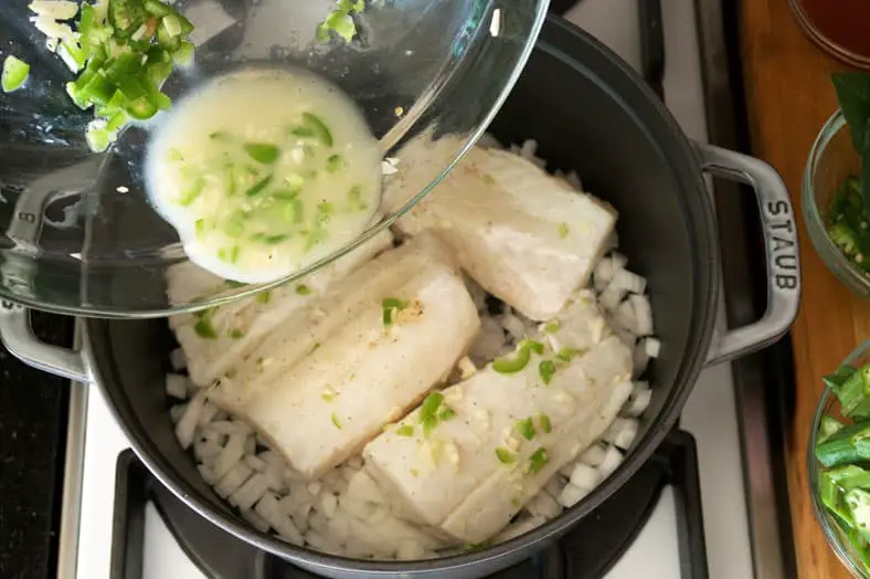 Adding marinated fish to pot for cooking