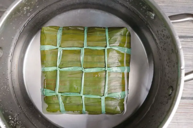 Cooking wrapped rice cake banana leaves parcel in a pot with water