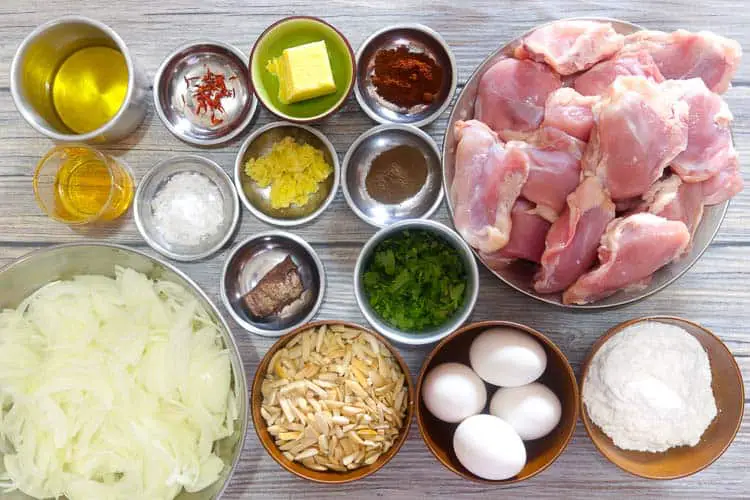 Top view of ingredients - chicken thighs, spices, eggs, flour in small bowls