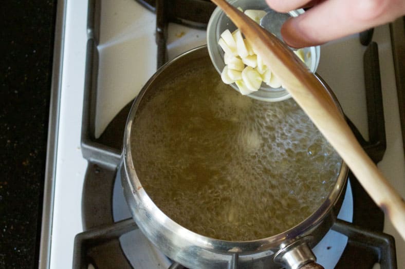 Boiling broth over medium heat and adding aromatic ingredients of your choice