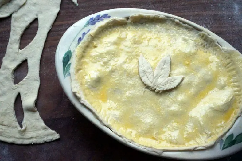 Cutting decorative petal from dough and placing it on top of casserole