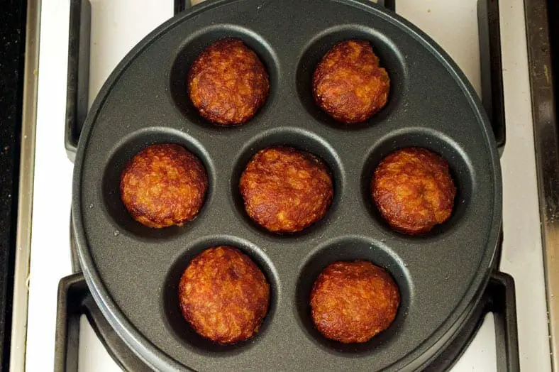 Fully cooked fritters in dimpled pan