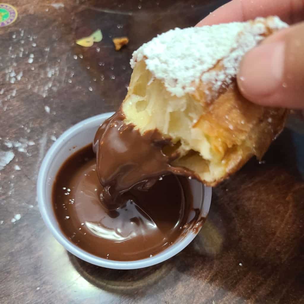 Hand holding a half eaten doughnut dipped in chocolate puree