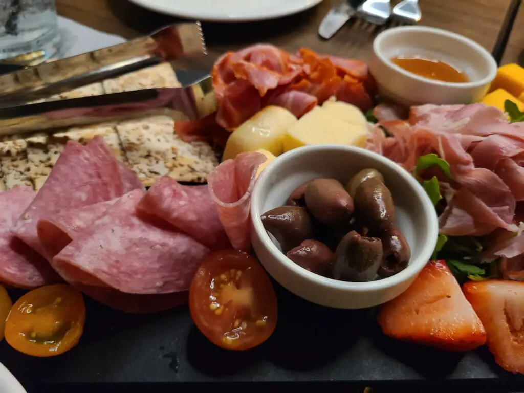 top view of charcuterie board with meats olives fruits and dips