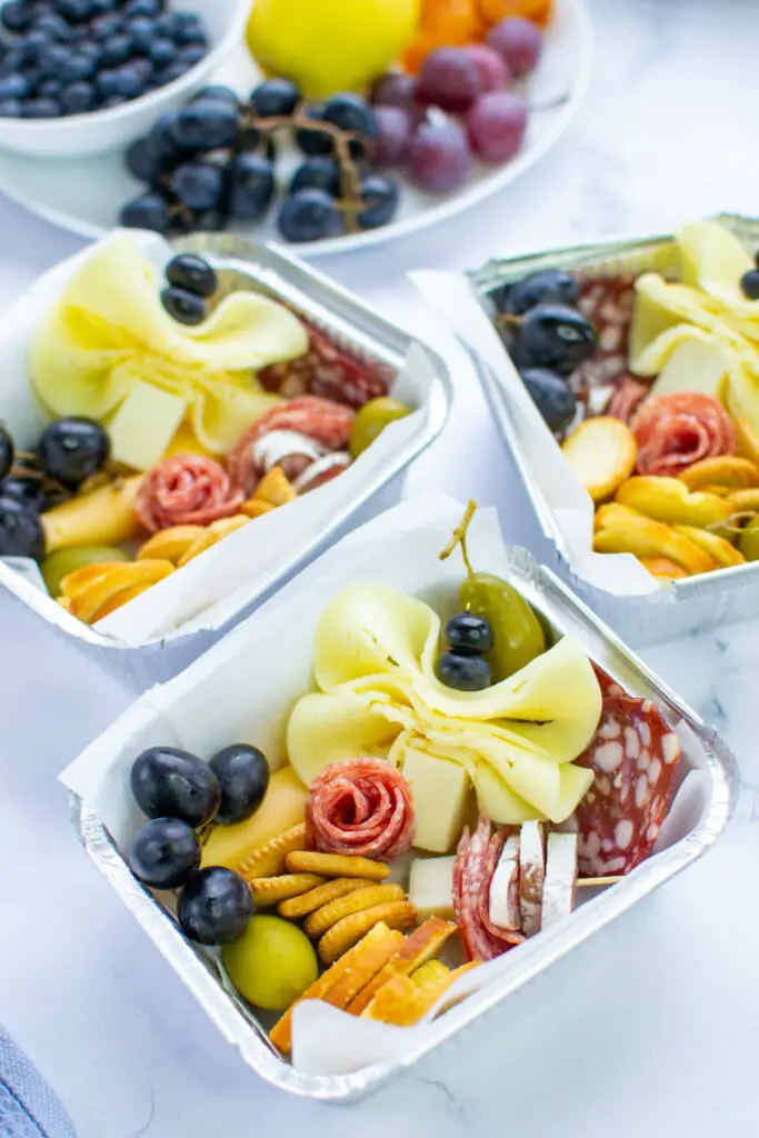 charcuterie mini boxes with fresh fruit display and a variety of cheese and crackers