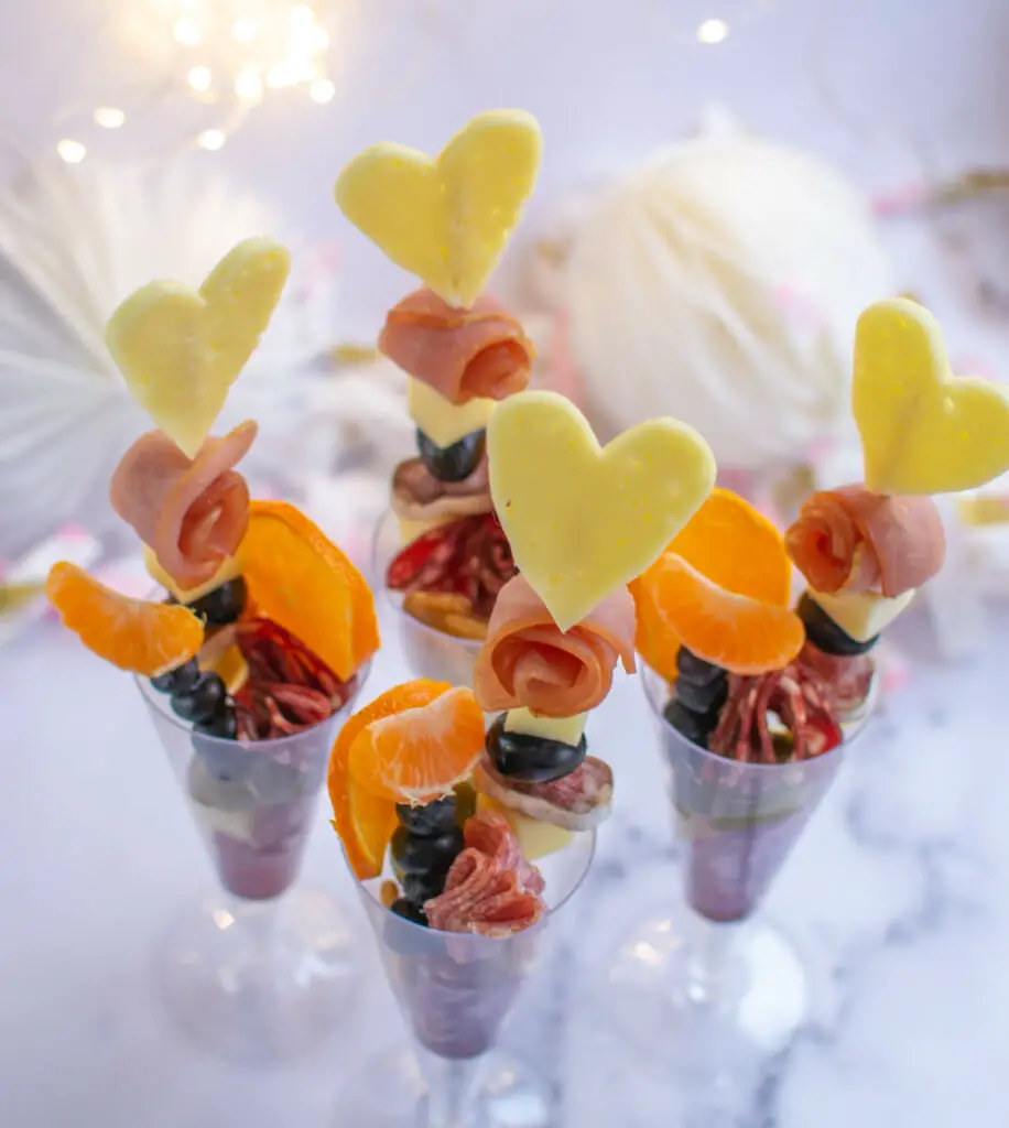 charcuterie cups for wedding - 4 skewers inside 4 champagne gups with sparkles in background