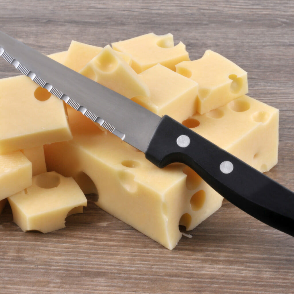 a knife lying across a block of gruyere cheese