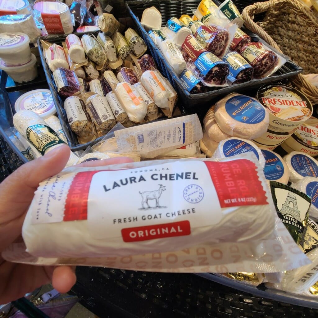 best cheese for charcuterie - goat cheese is a runner up - hand holding goat cheese at cheese counter at grocery store