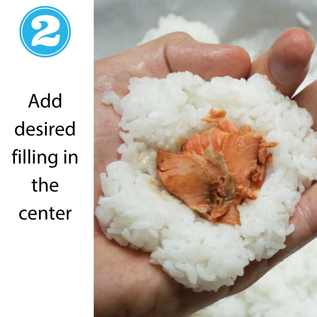 flattened rice ball in palm of hand with salmon placed in the center 