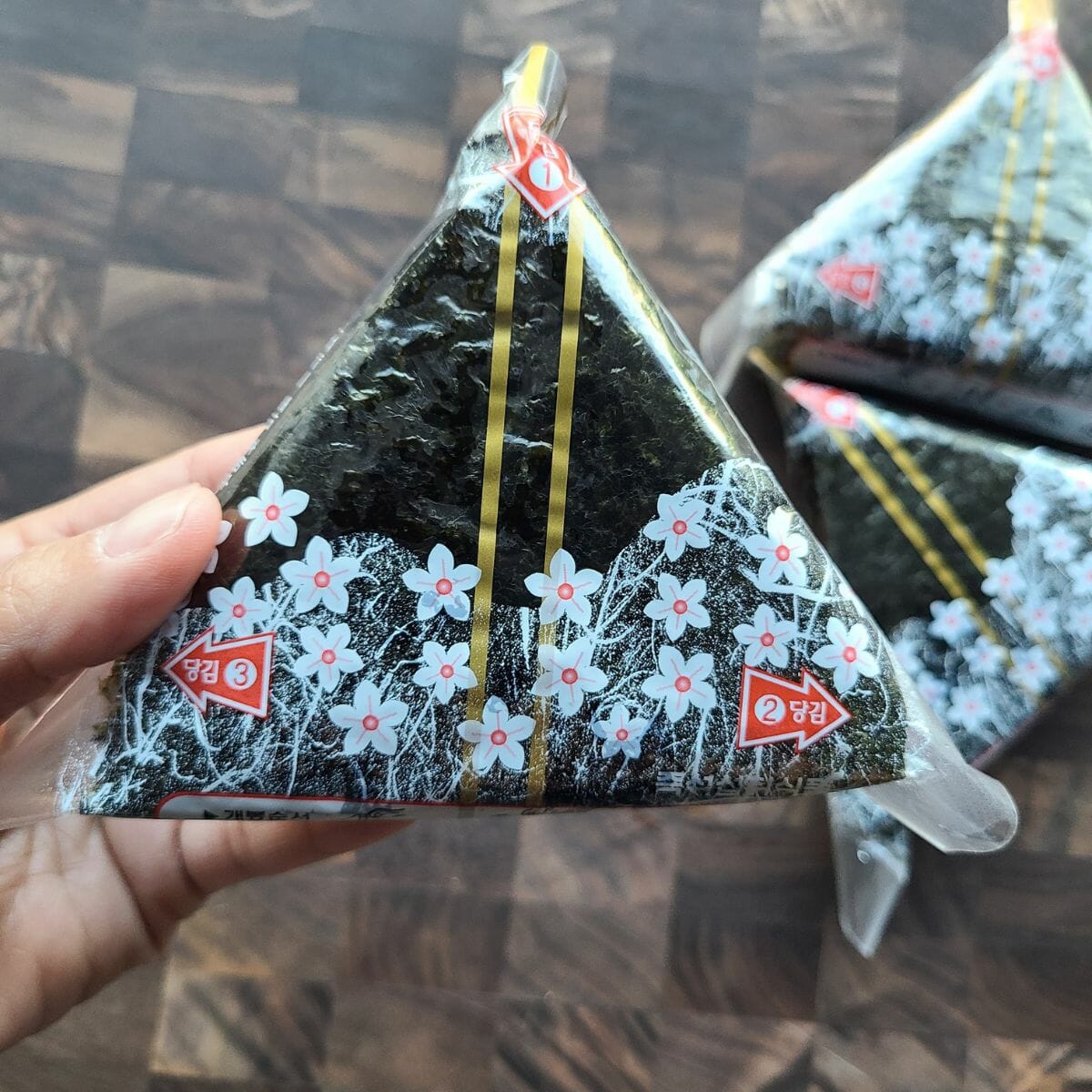 triangular shaped onigiri wrapped in individually wrapped plastic with flower decor