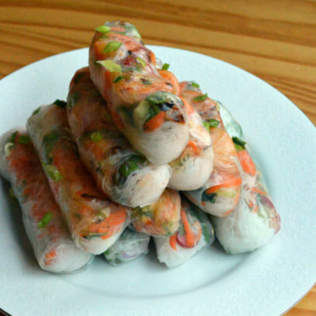 white ceramic plate piled with 10 rolls of vietnamese goi cuon spring rolls