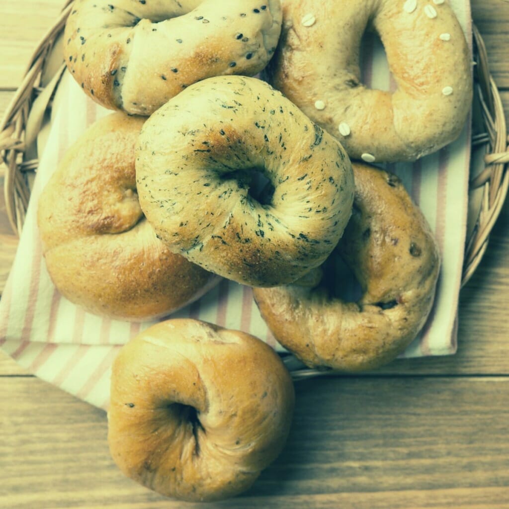 top view of several bagels arranged on top of a wicker basket with a cloth