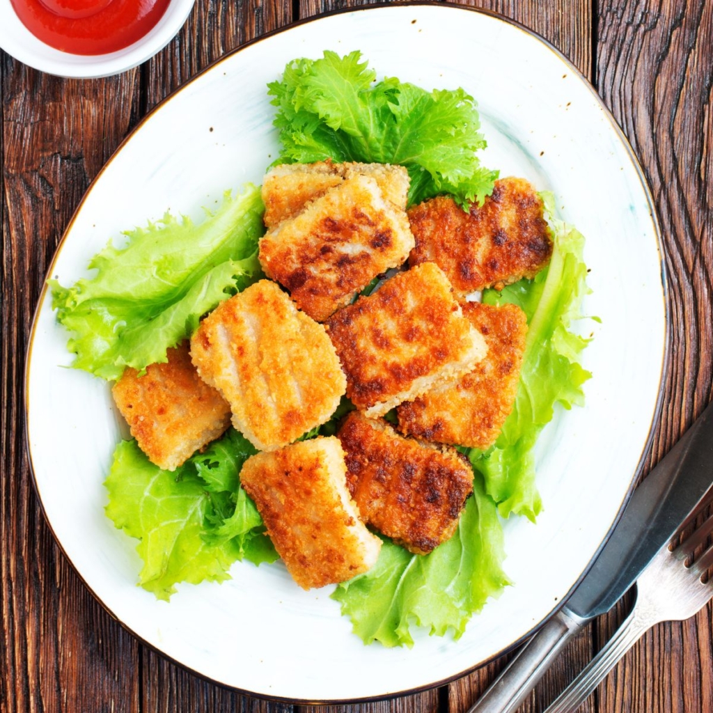 top view of a pile of fried monkfish on a white plate and garnished with lettuce