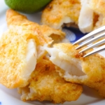 a fork pulling apart breaded monkfish