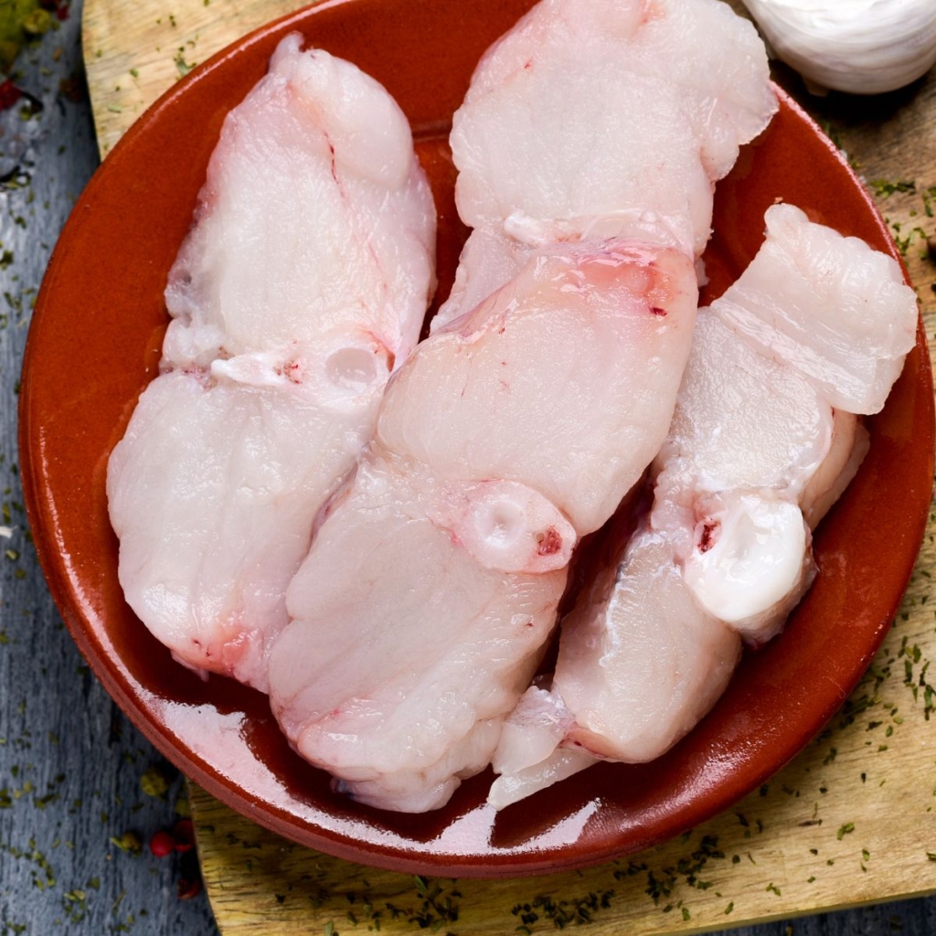 sliced raw monkfish on a red plate