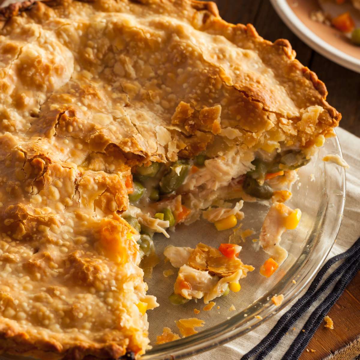 Chicken pot pie on a glass plate, set on a table with a towel