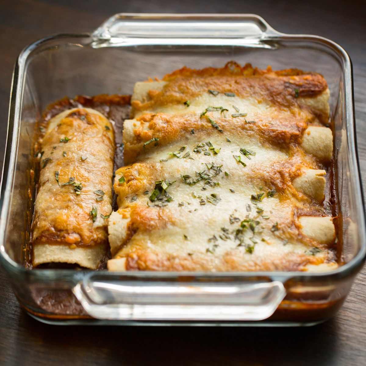 Enchiladas in a glass dish with golden cheese melting on top