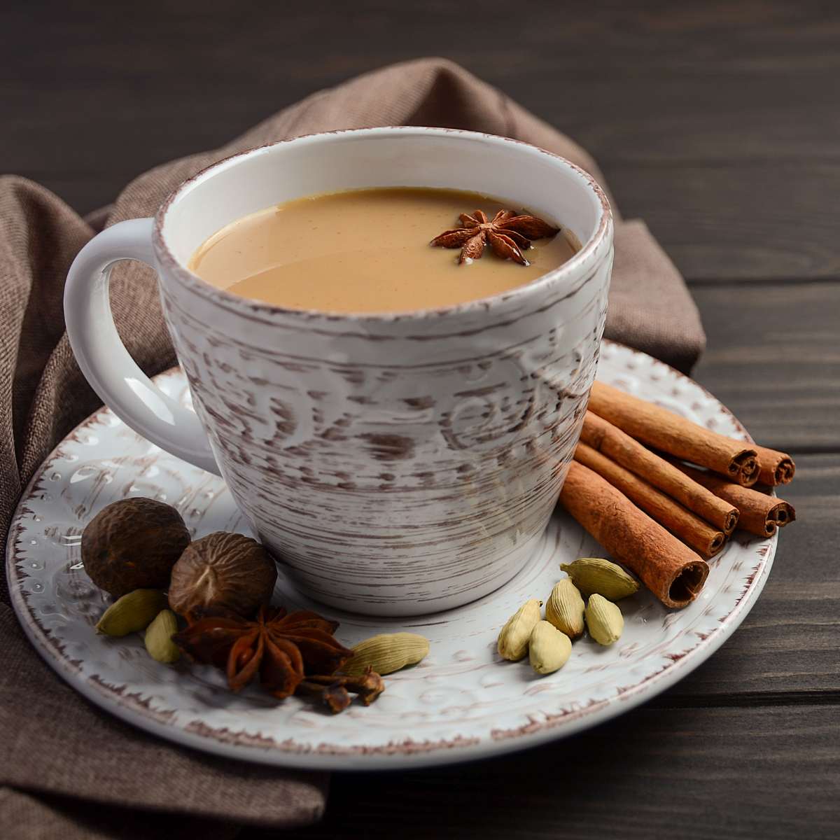 Spiced tea with Cinnamon, Cardamom, Star Anise, and Nutmeg in a saucer on table