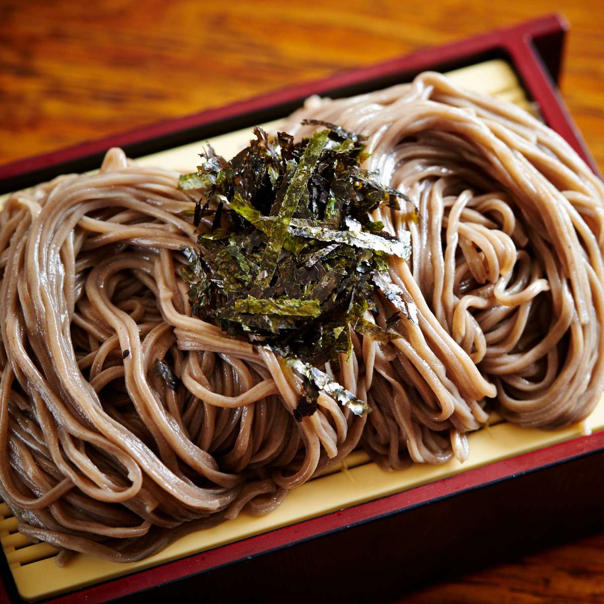 soba noodles topped with greens in a tray on the table
