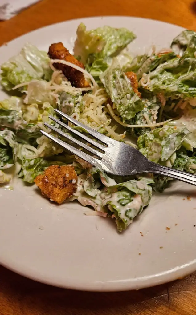 Caesar salad topped with croutons on a plate with fork.