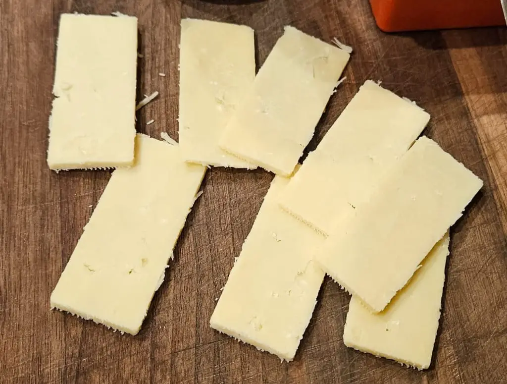 Cheese slices on a wooden serving board.