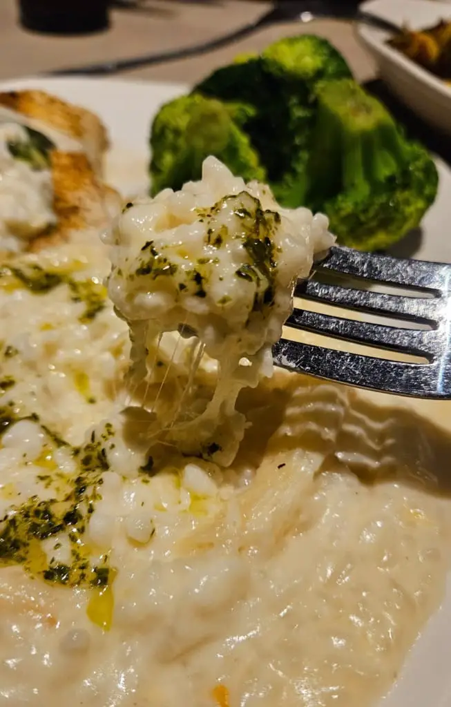 Creamy risotto lifted by fork from a plate.