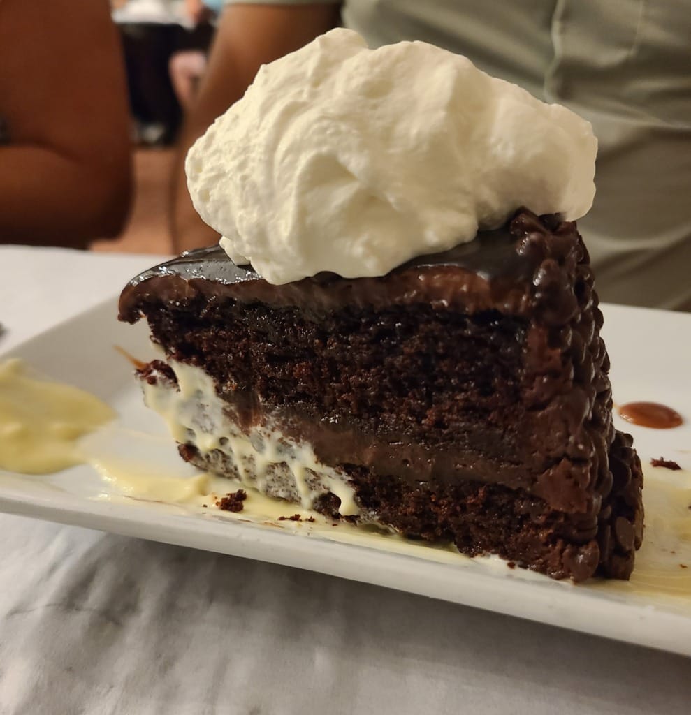 Chocolate cake topped with whipped cream on a plate.